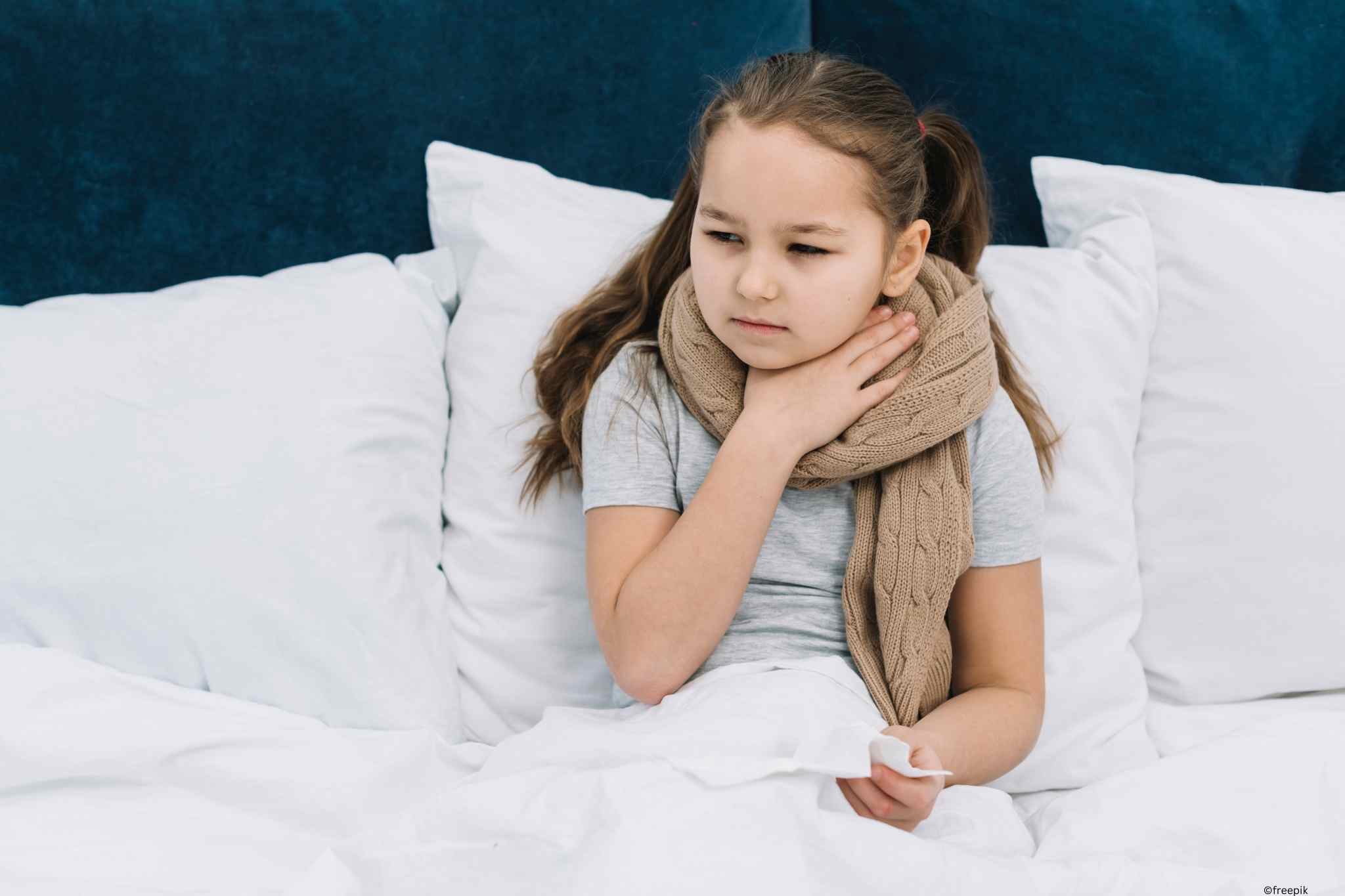 Mädchen im Bett mit einem dicken Schal um den Hals