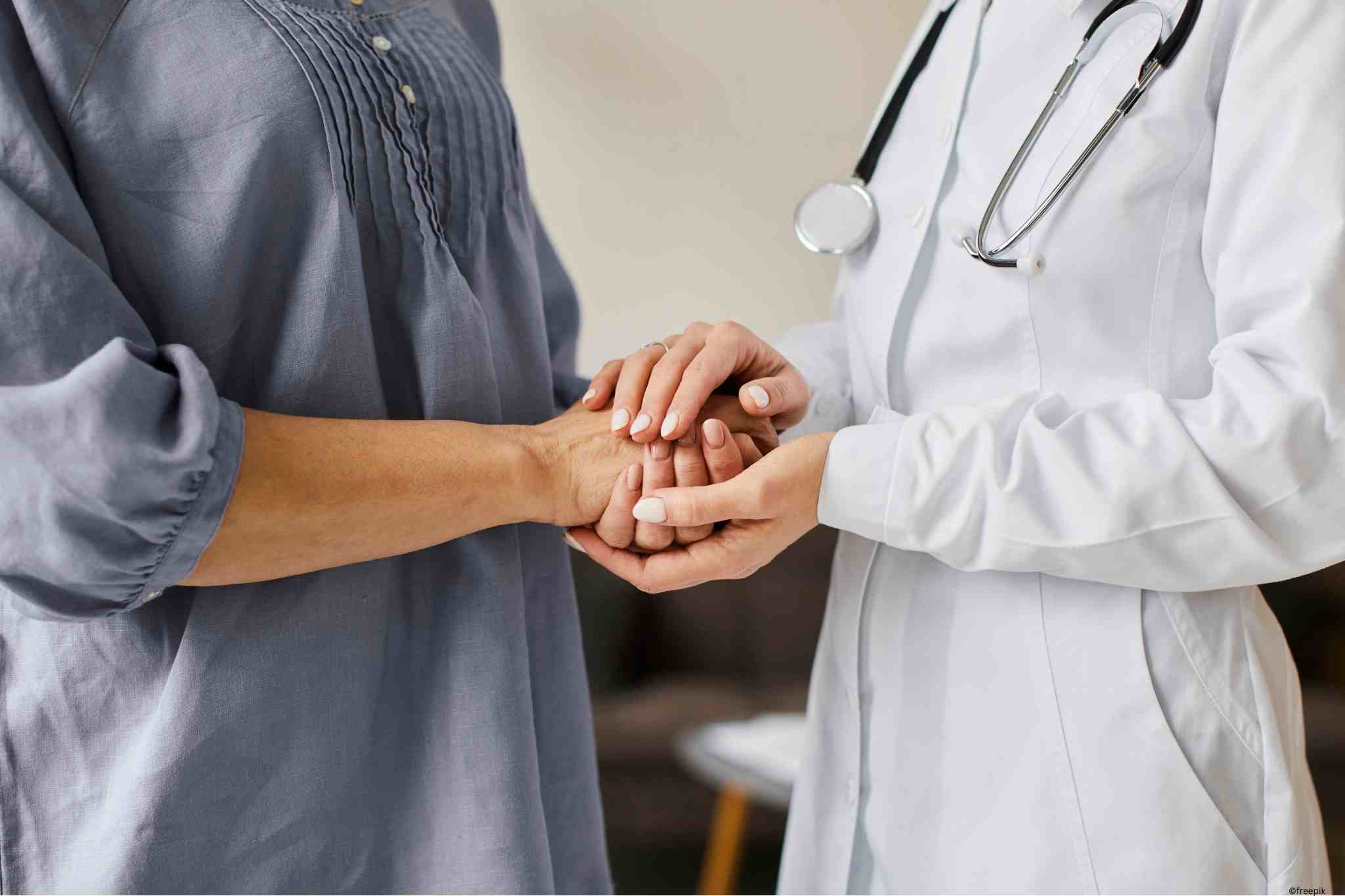 Ärztin, die die Hände einer Patientin hält